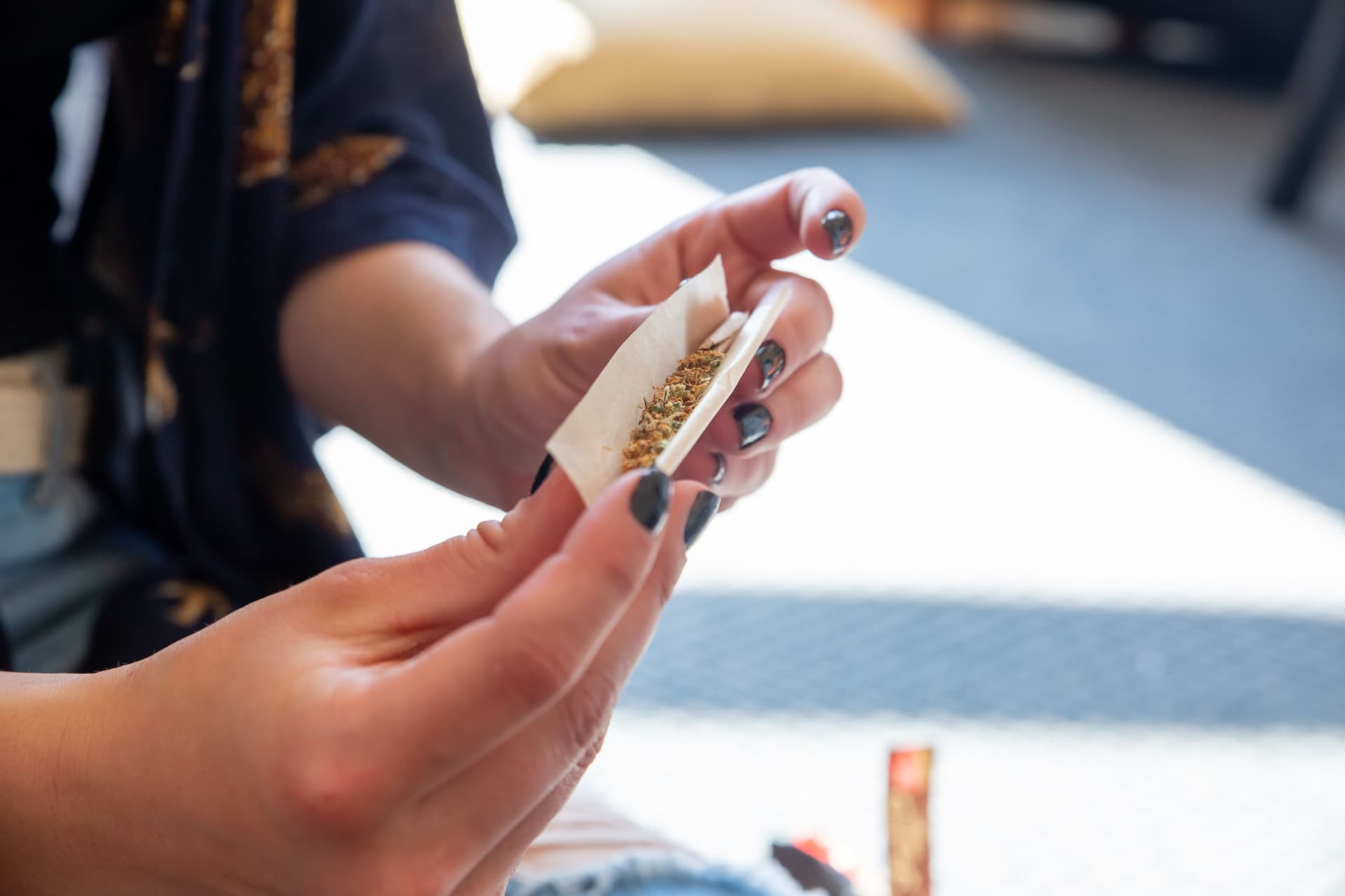 Hands rolling a cannabis pre-roll on a work surface
