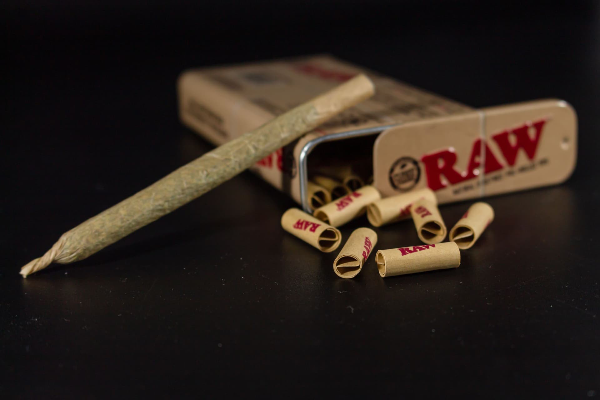 Rolling papers and a finished pre-roll arranged on a dark surface