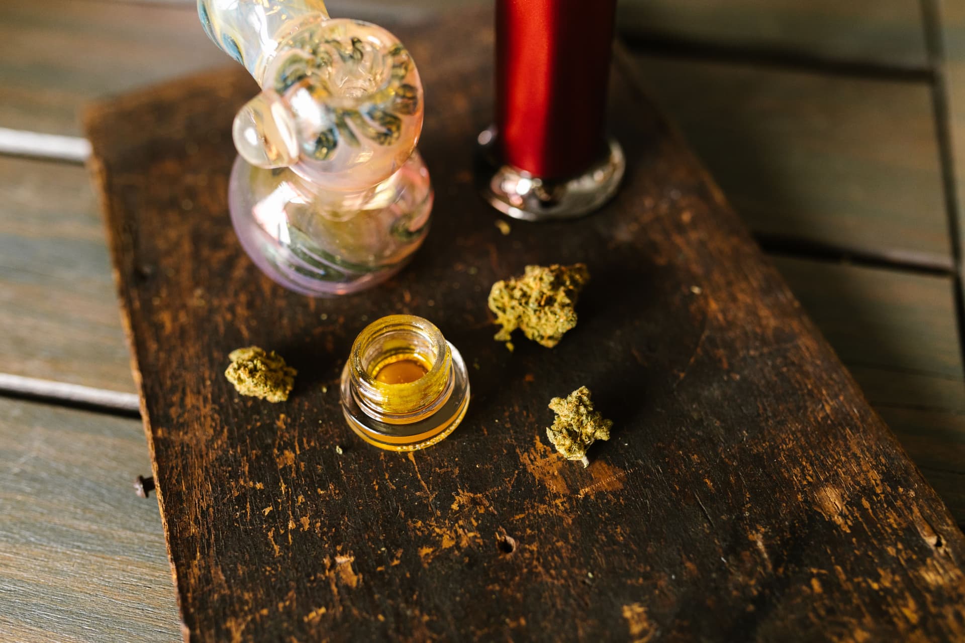 Cannabis flower beside a glass tool and golden concentrate